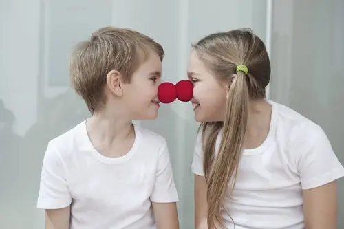 Kinder mit Clownsnasen grinsen sich an